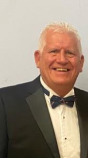 Smiling man in a suit and bow tie.