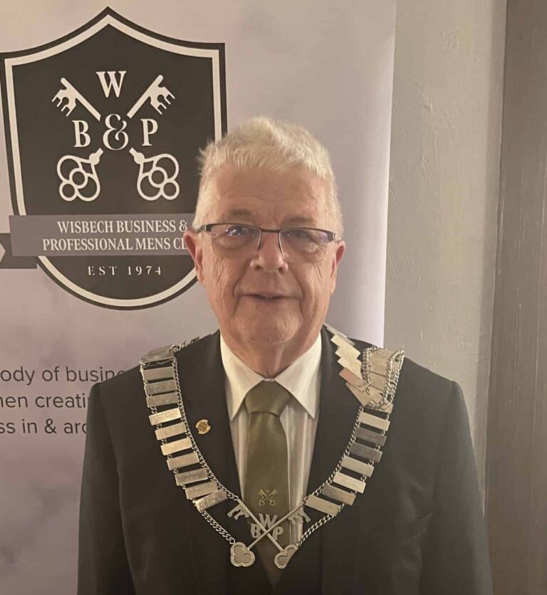 Man in formal attire with Wisbech Business sign.