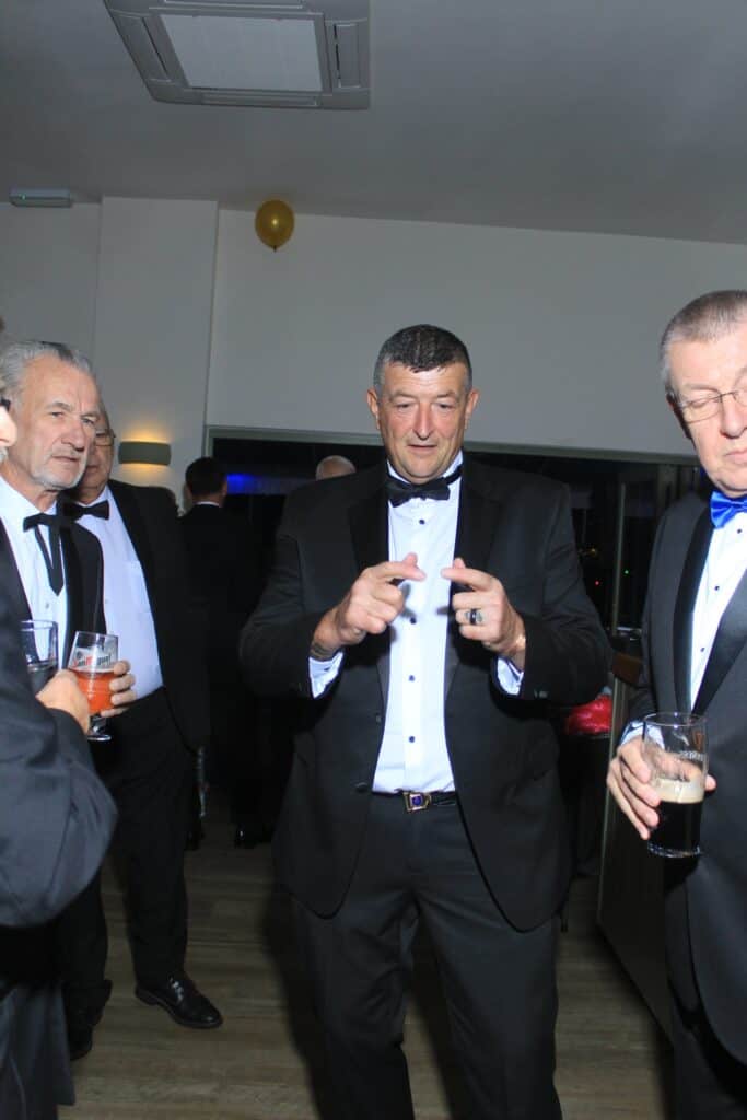 Men in tuxedos drinking and socializing.